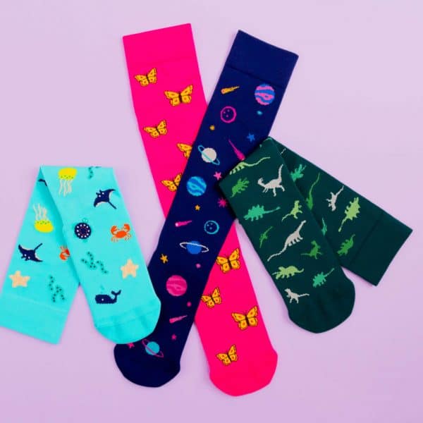 Compression socks all piled in a bunch, the designs are sea creatures, space, butterflies and dinosaur.