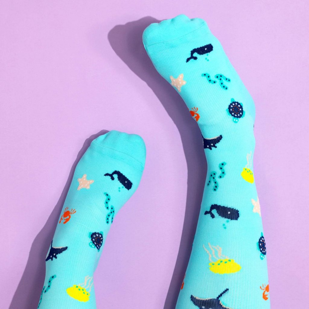 Turquoise compression socks with sea life pattern on lilac background